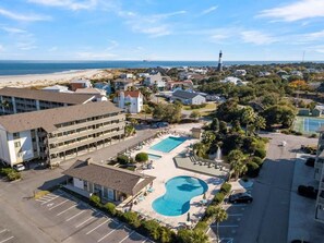 An aerial view of a hotel with a swimming pool, parking lot, and beachfront view. - Lighthouse Point 3B | Great View, Pool Access (Tybee Island)
