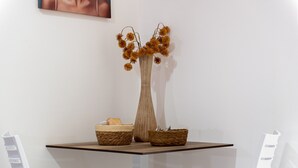 A table with a vase of dried flowers, two woven baskets, and a framed picture on the wall. - Room 'Perla Marina - Scala Dei Turchi' with Balcony, Wi-Fi, Air Conditioning and Shared Kitchen (Realmonte)