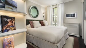 A neatly arranged bedroom with a large bed, a bedside table with books, a mirror, and a window with curtains. - Dimora Elvezia Milano (Milan)