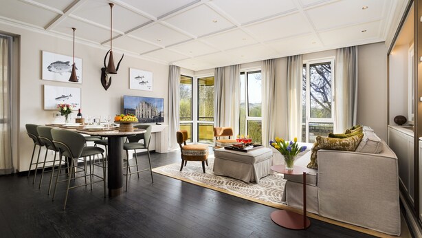 A spacious living area with a dining table, chairs, a sofa, and a coffee table. There are large windows providing natural light and a view of the outdoors. - Dimora Elvezia Milano (Milan)
