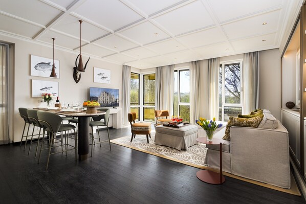 A spacious living area with a dining table, chairs, a sofa, and a coffee table. There are large windows providing natural light and a view of the outdoors. - Dimora Elvezia Milano (Milan)