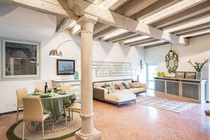 A spacious living area with a dining table, sofa, and a large window. - La Loggetta Grand Canal San Marco (Venice)