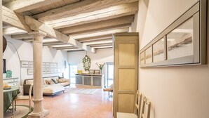 A spacious room with a high ceiling, exposed beams, a large window, and a view of the cityscape. - La Loggetta Grand Canal San Marco (Venice)