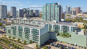 A high-rise building with multiple floors, large windows, and a parking lot in front.