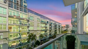 A modern multi-story hotel with balconies, a swimming pool, and a cityscape view.