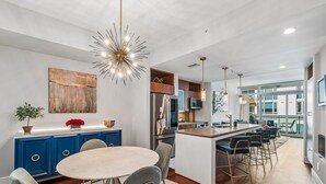 A modern kitchen with a central island, blue cabinetry, and a dining area with a round table and chairs.