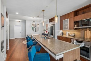 A modern kitchen with a central island, bar stools, stainless steel appliances, and pendant lighting. - Urban Fun: Lightning Fans, Concerts & Conventions (Tampa)
