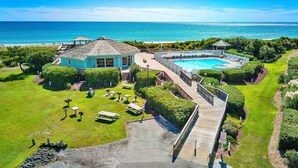 A resort with a pool, a deck, and a view of the ocean. - 1BR Condo w/ Pools, Balcony Views & Easy Beach Access | Pebble Beach (Emerald Isle)