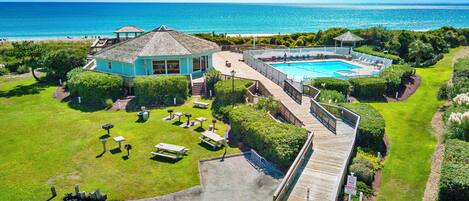 A resort with a pool, a deck, and a view of the ocean.