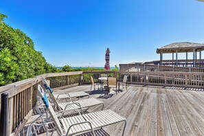 Eine Holzterrasse mit Sitzgelegenheiten im Freien, einem Gazebo und Blick auf das Meer.