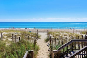 A sandy beach with a wooden walkway leading to the water. - Cozy Oceanside 1BR | Indoor + Outdoor Pools (Emerald Isle)