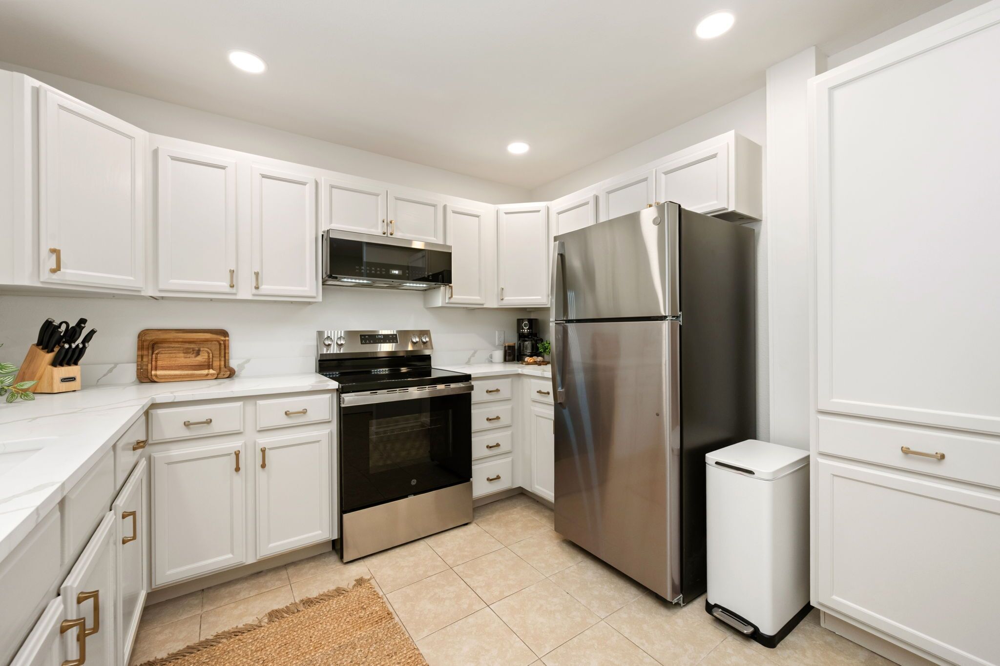 A modern kitchen with white cabinetry, stainless steel appliances, and a built-in oven.