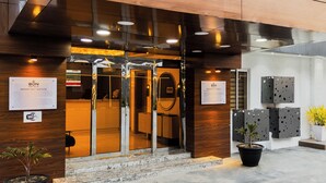 En hotellentrén med en receptionsdisk, en skylt och en krukväxt.