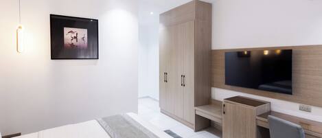 Une chambre d’hôtel moderne équipée d’un lit, d’un bureau, d’une chaise, d’une télévision et d’une armoire.