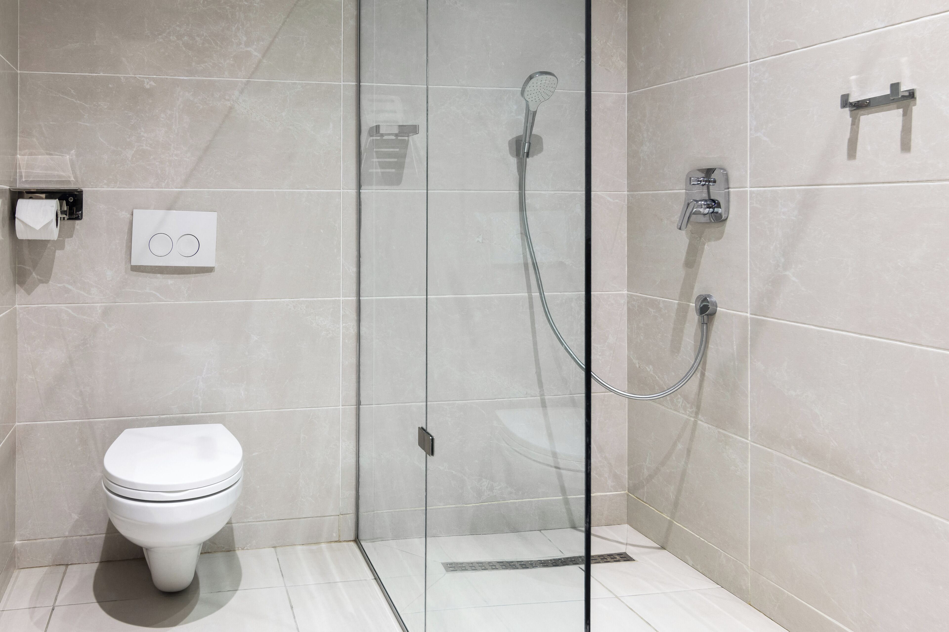 A modern bathroom with a glass-enclosed shower, a toilet, and a towel rack.
