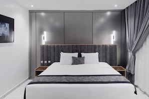 A modern hotel room with a large bed, wooden headboard, bedside tables, and a framed picture on the wall. - BON Hotel Conservation Lekki (Lekki)