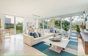 A spacious living room with a large sofa, a coffee table, and a dining area with chairs. - Luxury Villa Cap Cana (Punta Cana)