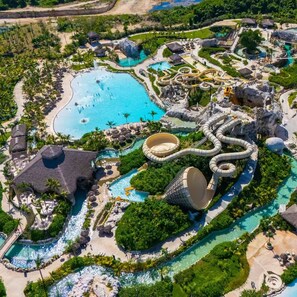 Vista aérea de um resort com várias piscinas, toboáguas e vegetação exuberante.