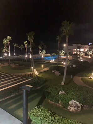 Ein beleuchteter Resort-Bereich bei Nacht mit Pool, Palmen und gepflegten Wegen.