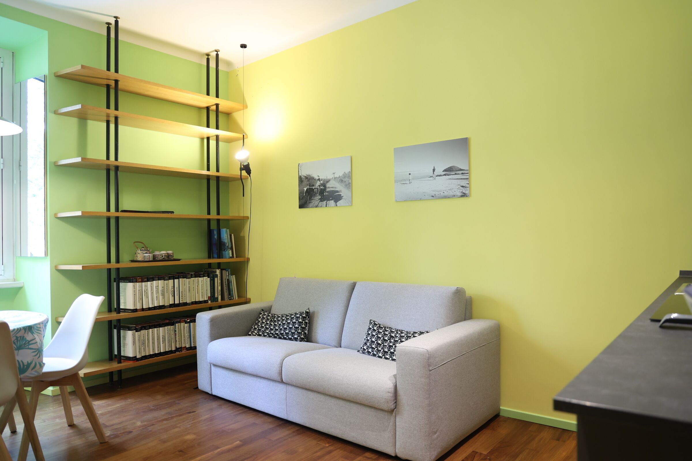 A living room with a sofa, a bookshelf, and two framed pictures on the wall.