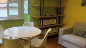 Ein Zimmer mit einem runden Tisch, zwei Stühlen, einer Couch und einem Bücherregal.