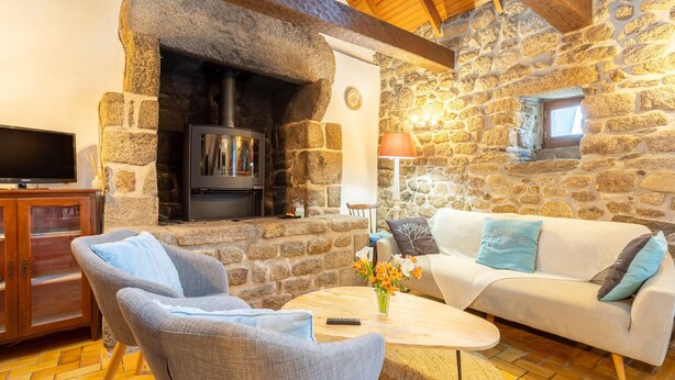 A stone fireplace, a television, a sofa, and a coffee table in a cozy room. - Breton Character House with Shared Pool (Ergué-Gabéric)