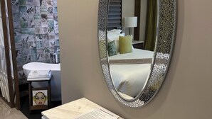 A hotel room with a marble vanity, a mirror with a decorative frame, a bed with a green pillow, and a bathroom with a white sink and a towel rack. - Luxury King bed + bath Junior Suite + kitchenette. 2 guest plus all inclusive. (Cancún)