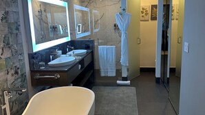 A modern bathroom with a freestanding bathtub, a vanity with a large mirror, and a walk-in shower. - Luxury King bed + bath Junior Suite + kitchenette. 2 guest plus all inclusive. (Cancún)