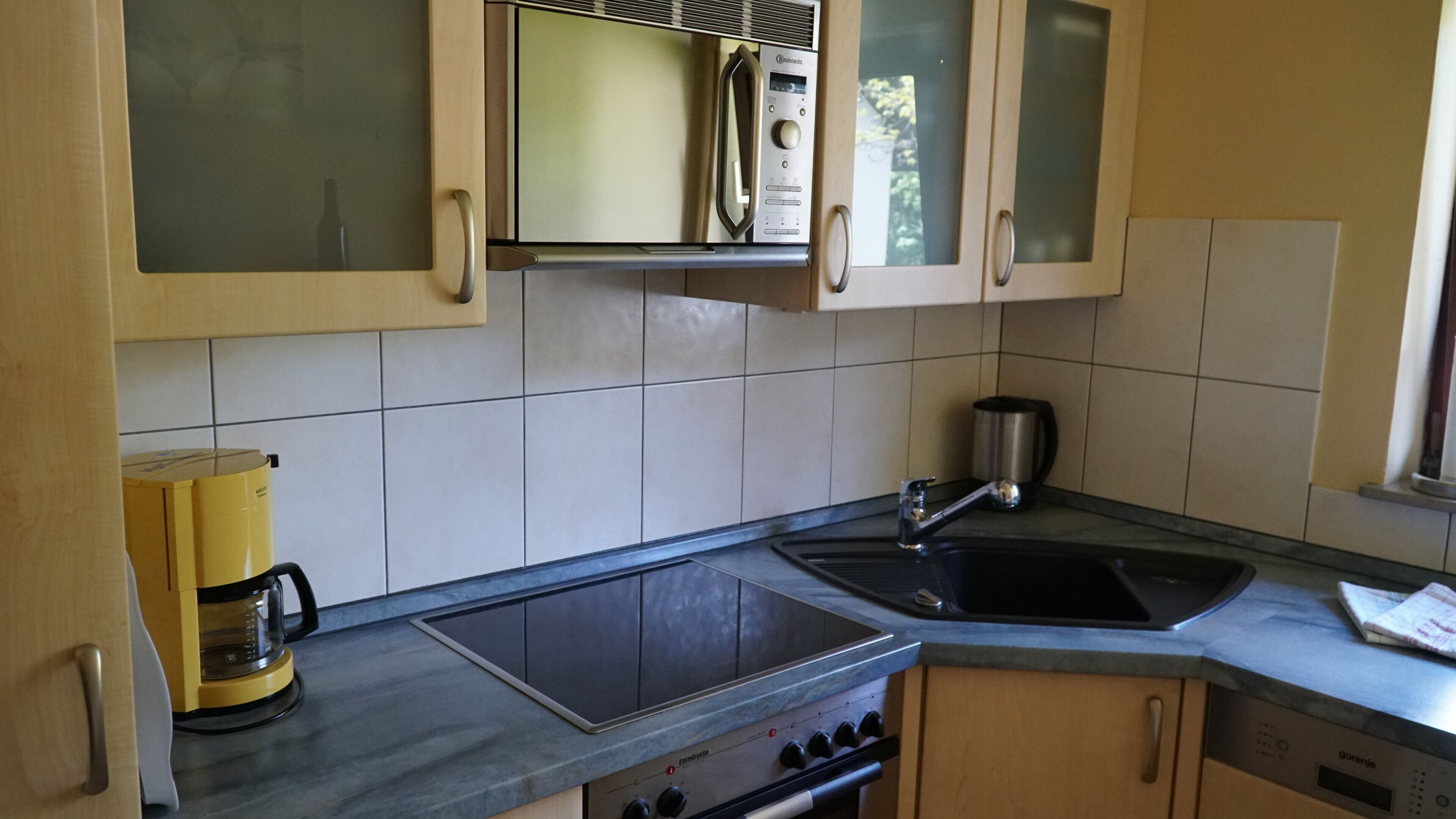 A kitchen with a microwave, stove, sink, and coffee maker.