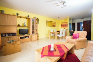 A living room with a TV, wooden furniture, a dining area, and a red rug. - Vacation apartment Christine incl. Hochschwarzwald-Card in the beautiful Titisee! (Titisee-Neustadt)