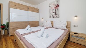 A double bed with white linens, a wooden headboard, and a wall-mounted artwork. - Charming apartment with pool and parking in Crikvenica (Crikvenica)