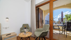 A room with a wooden floor, a small round table with a bottle and glasses, two upholstered chairs, a wooden cabinet, and a sliding glass door leading to an outdoor area with a table and chairs. - Charming apartment with pool and parking in Crikvenica (Crikvenica)