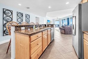 A kitchen with granite countertops, wooden cabinets, and a built-in refrigerator. - 🐚Gulf Front Views | Balcony | Pool | Palazzo 908🌴 (Panama City Beach)