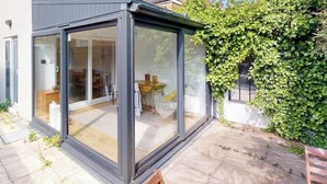 Ein modernes Haus mit Wintergarten, Terrasse und Garten.
