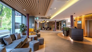 A modern lobby with a reception desk, seating area, and large windows.