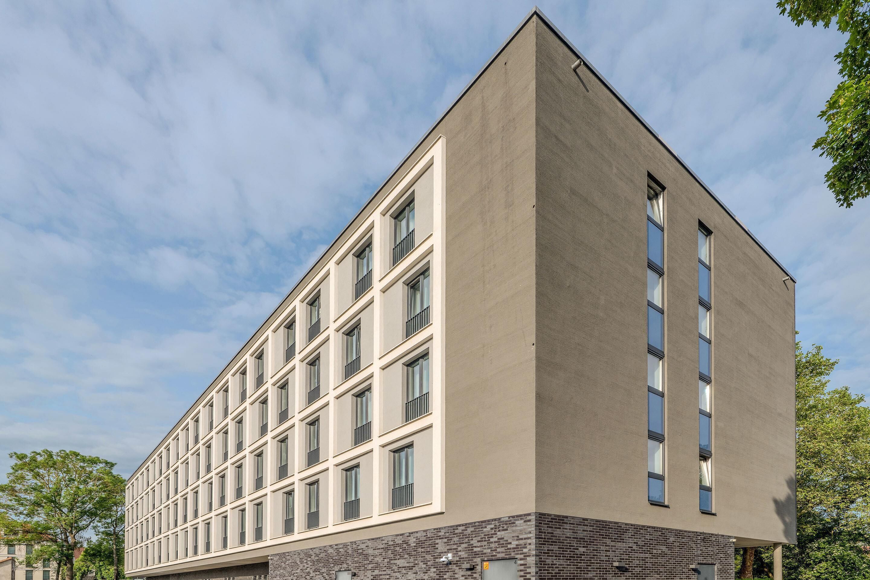 Ein modernes Gebäude mit flachem Dach, großen Fenstern und einer Ziegelbasis.