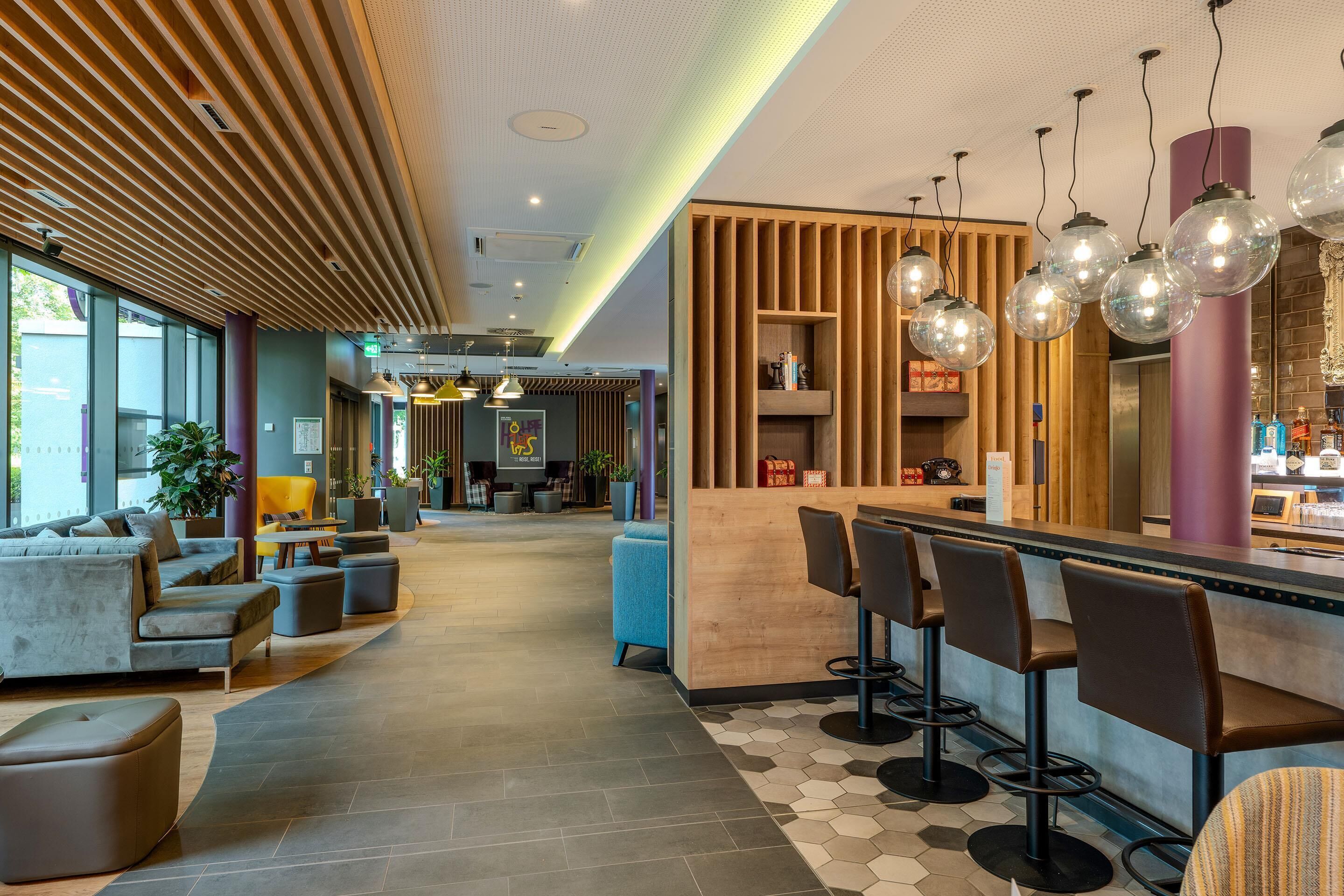 A modern bar area with a wooden counter, bar stools, and pendant lighting.