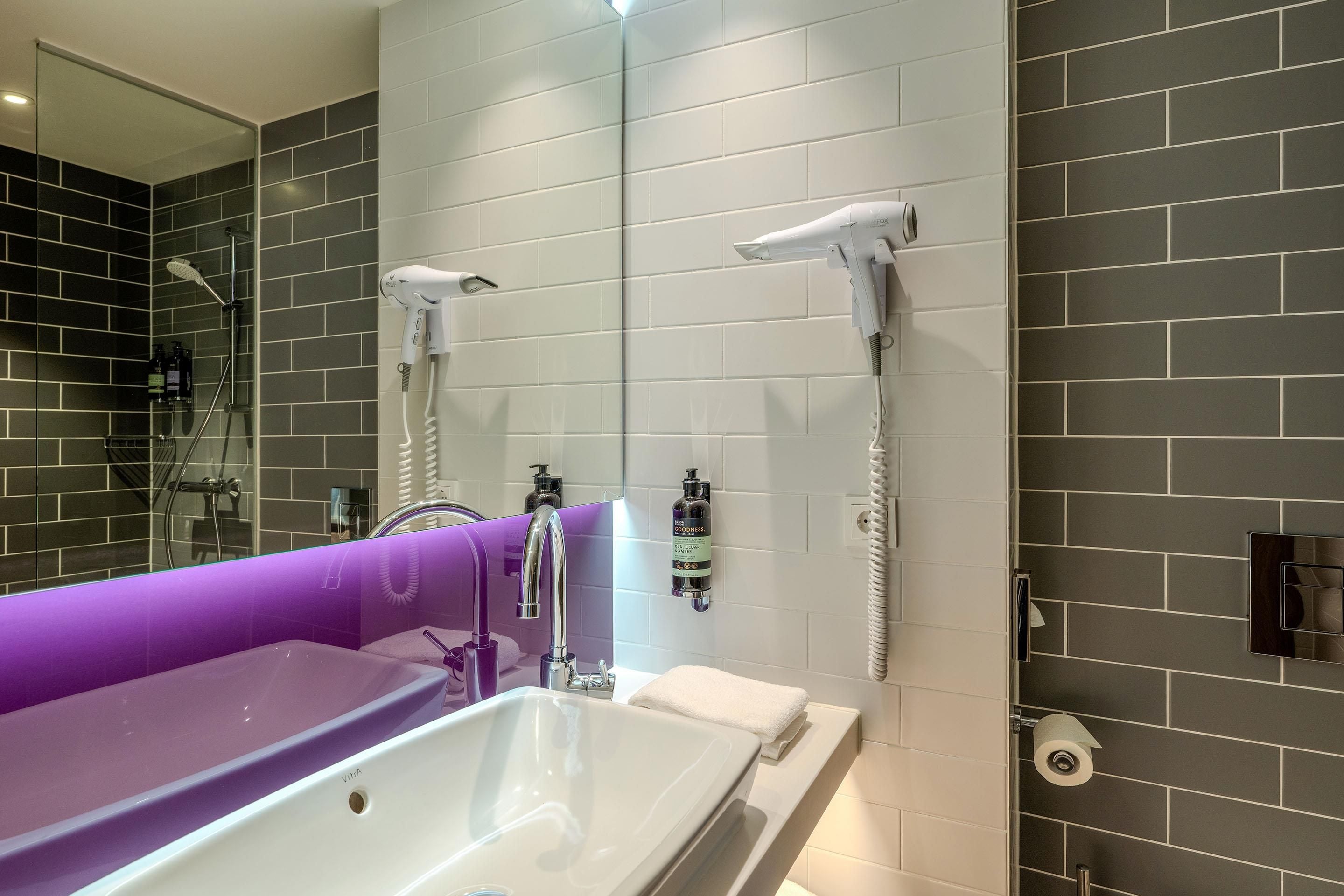 A modern bathroom with a large bathtub, a shower area, and two wall-mounted hair dryers.