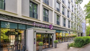 A Premier Inn hotel with a modern facade, large windows, and outdoor seating visible through the glass doors.