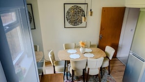 Una cucina funzionale con frigorifero, un tavolo da pranzo con sedie e una porta in legno.