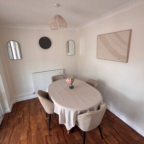 Un espace repas comprenant une table ronde, des chaises, un luminaire suspendu et des miroirs fixés au mur.