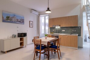Een moderne keuken met houten kastjes, een eettafel met blauwe stoelen, een magnetron en een spoelbak.