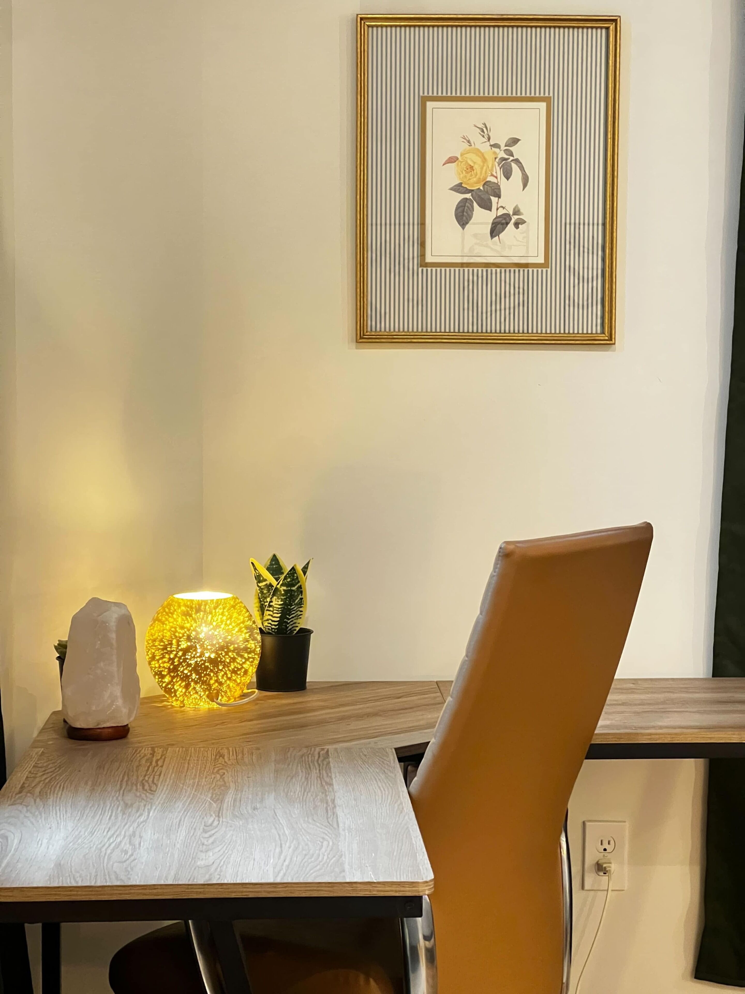 A dining area with a table, chair, decorative items, and a framed picture on the wall.