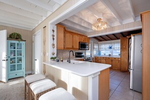 A kitchen with wooden cabinets, a white island, a chandelier, and a refrigerator.