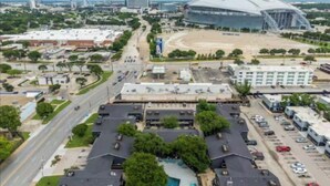 Un grand parking avec plusieurs bâtiments, un stade et une route.