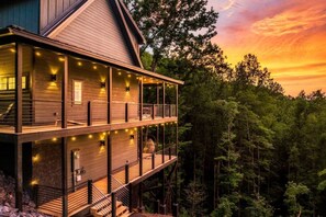 Eine zweistöckige Holzhütte mit einem Balkon, umgeben von einem Wald.