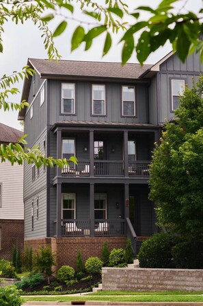 A two-story building with a balcony on the second floor, surrounded by greenery. - New Luxe East Nashville Home • Sleeps 6 Near DWTN (Nashville)