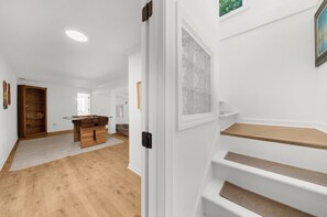 Een modern interieur met een trap, houten vloeren en een uitzicht op een stadsgezicht door een raam.