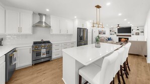 Una cocina moderna con armarios blancos, electrodomésticos de acero inoxidable y una isla central.
