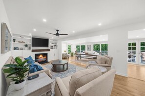 Un salón comedor amplio con chimenea, ventilador de techo y un gran ventanal con vistas a una terraza.